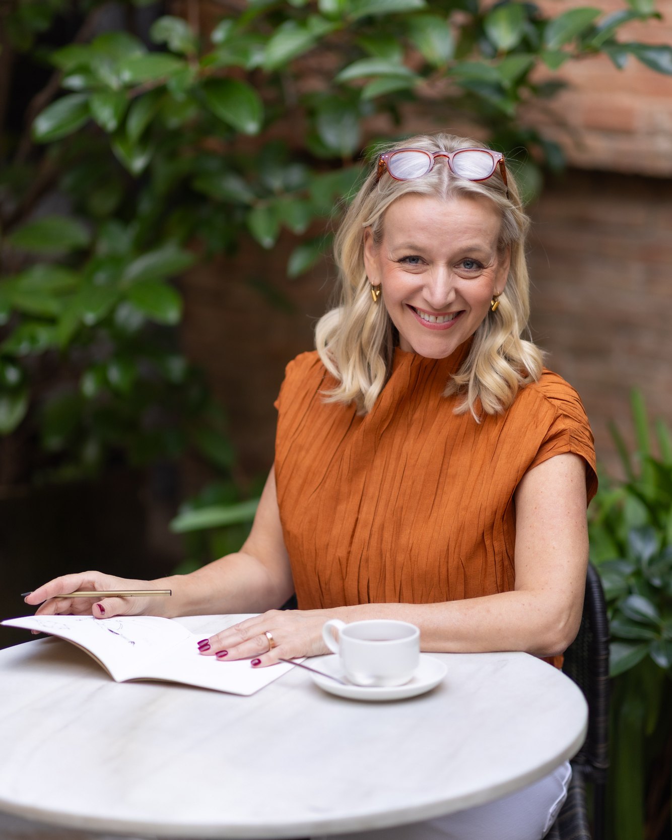 Cindy Hermsen, sentada en una terraza con un cuaderno y un café